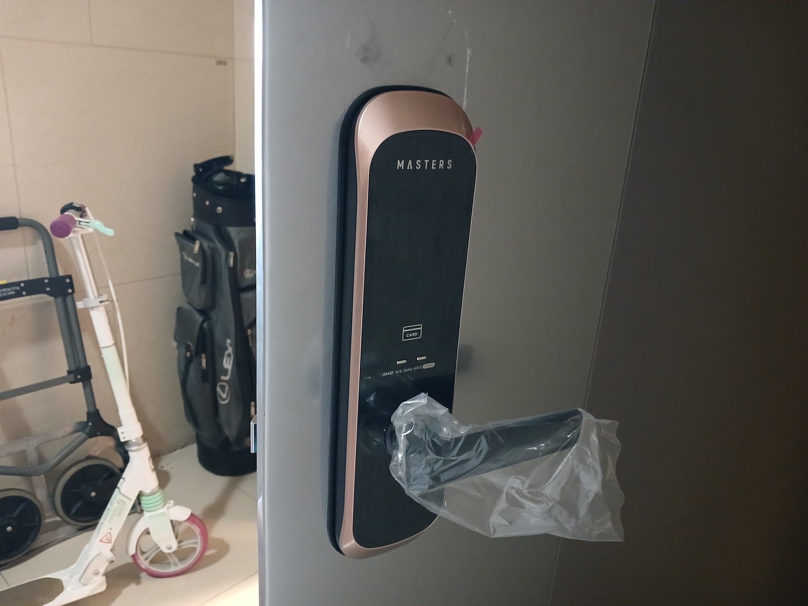 일산서구 주엽2동 출장 — 회색 문에 단 검은 레버형 도어락, 레버에 씌운 투명 비닐과 분홍색 테이프